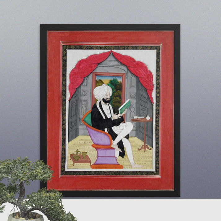 A Sikh Sardar reading from a book, seated in front of a window - Framed Print - SRI ASDHUJ